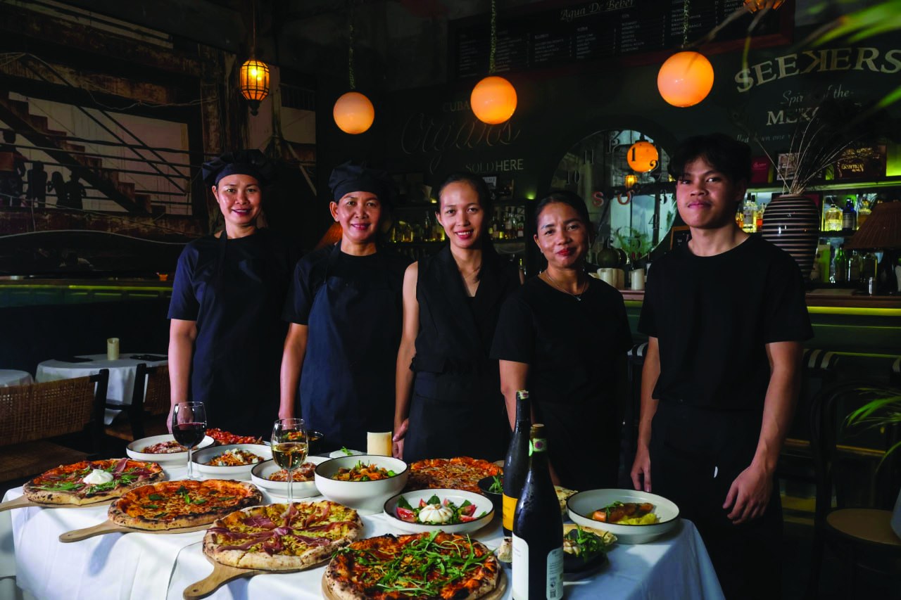 The Mr. CIAO team behind a table full of pizzas and dishes