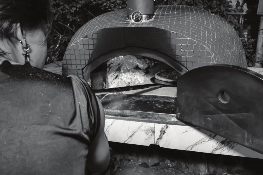 Pizzaiolo working the wood-fired oven